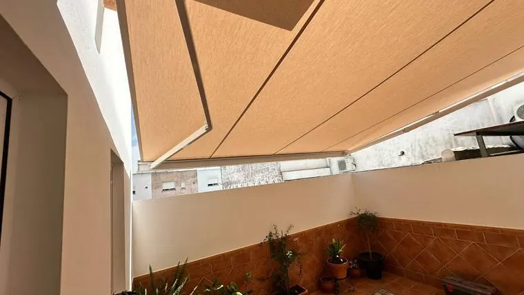 Dos toldos de brazo articulado abiertos sobre la terraza de una casa
