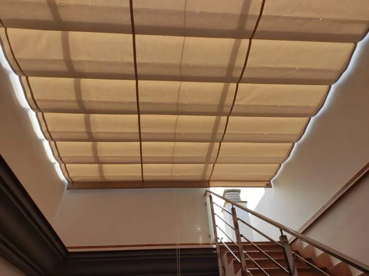 Toldo corredera de lona beige cubriendo el hueco de escalera de una vivienda