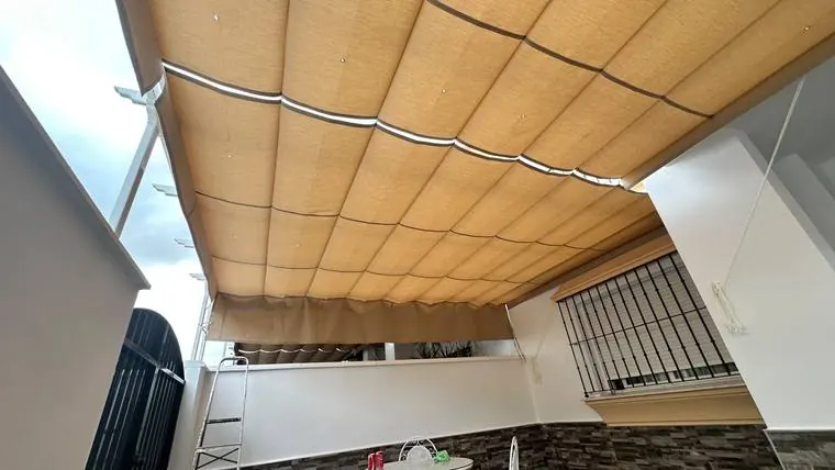 Toldo corredera de lona beige cubriendo el patio de una vivienda en Lebrija